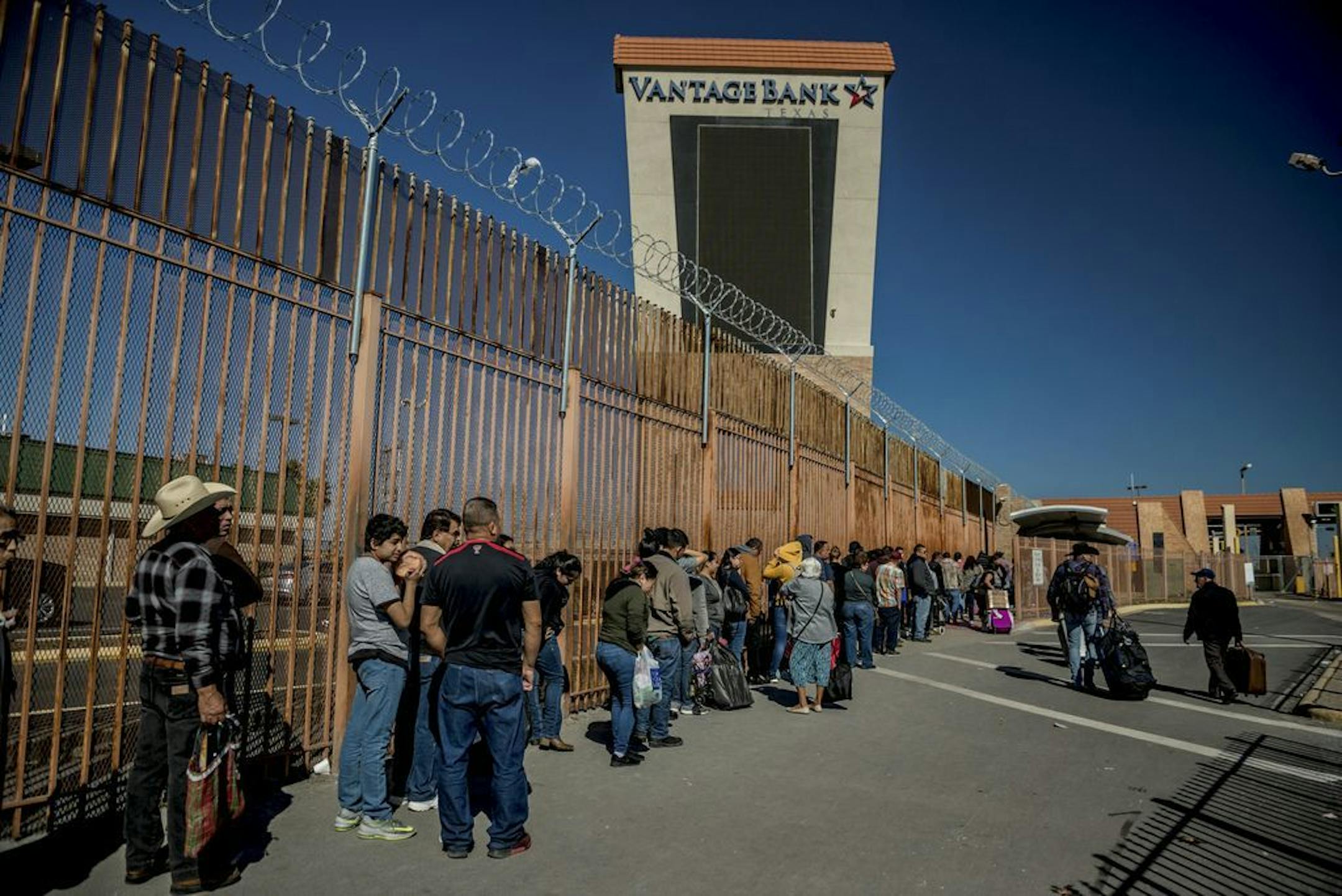 People, many of them migrants, wait in line to cross the border from Reynosa, Mexico to McAllen, Texas, Jan. 5, 2019.