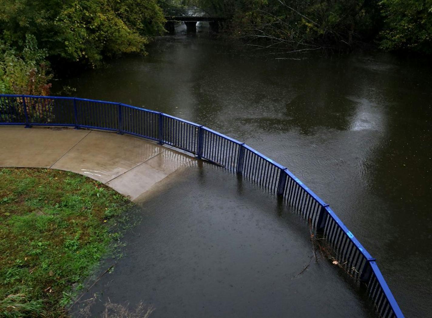 High water from the Canon River spills onto a walkway near Slevin Park Wednesday, Oct. 2, 2019, in Farifault, MN.