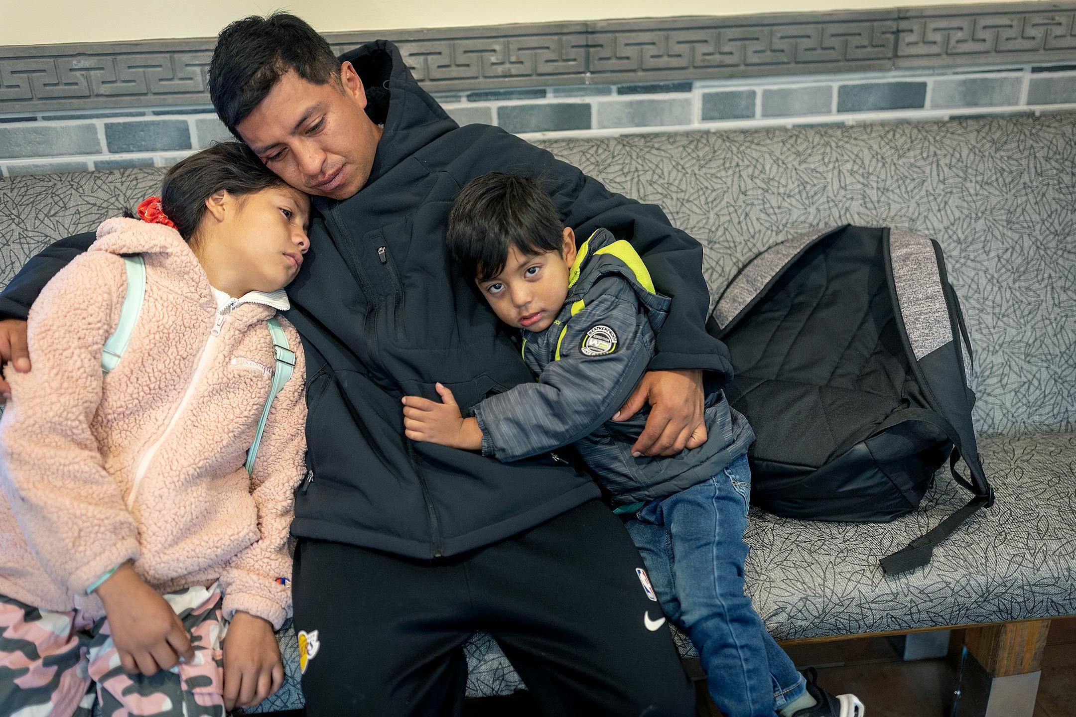 Jhon Requelme hugs his children during a visit to Lake Street in Minneapolis on Saturday, Oct. 21, 2023. He fled Ecuador with his family via the dangerous jungle known as the Darien Gap and ended up on the Arizona border before making it to Minnesota. His family was placed in a shelter downtown and equipped with three meals a day, day care and transportation to school for their daughter.
