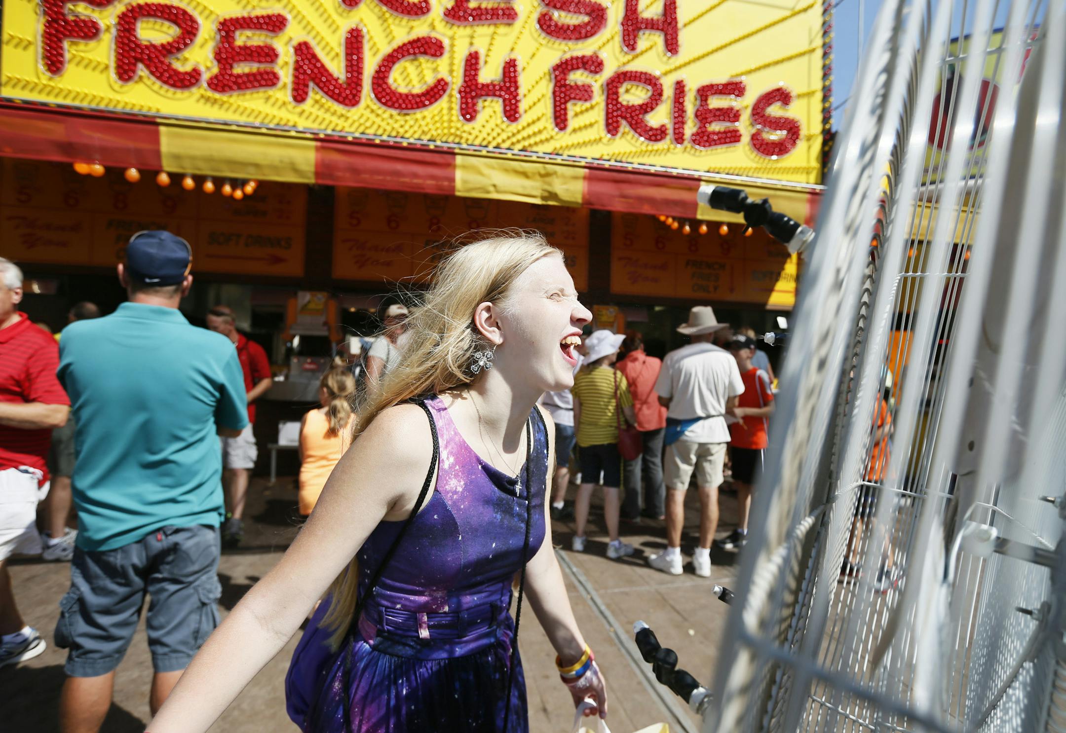 Two fans help keep Anika Hovey cool in front of the french fries booth at the Minnesota State Fair Wednesday Aug 28 ,2013 in Falcon Heights , MN. ] JERRY HOLT ‚Ä¢ jerry.holt@startribune.com