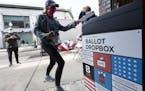 A woman places her ballot in a dropbox after voting at Fenway Park, Saturday, Oct. 17, 2020, in Boston.