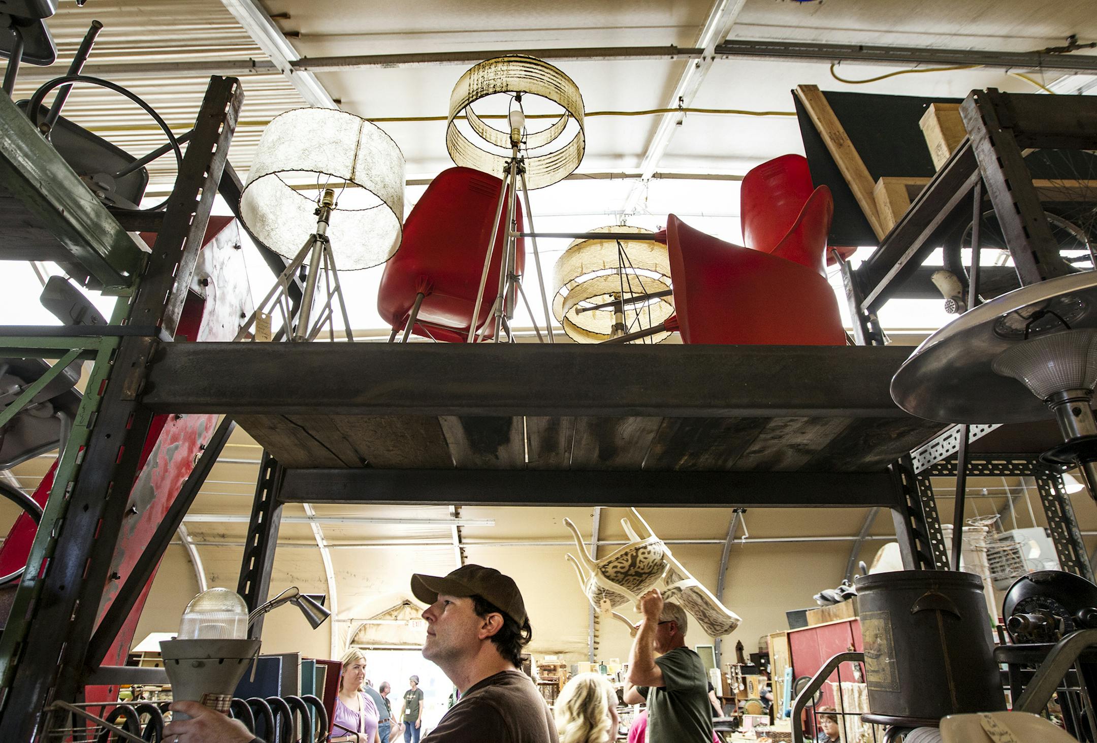 Daniel Dempster (in hat) of Mankato looks over the retro furniture and trinkets offered by Olde Town Creamery, a vintage shop based in Maple Lake, at the Junk Bonanza at Canterbury Park in Shakopee.