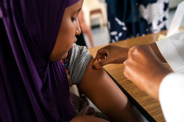 Amal Elmoge, 12, received her second dose of the COVID-19 vaccine from Asha Hassan during a community vaccination event at the Chase House Apartments 