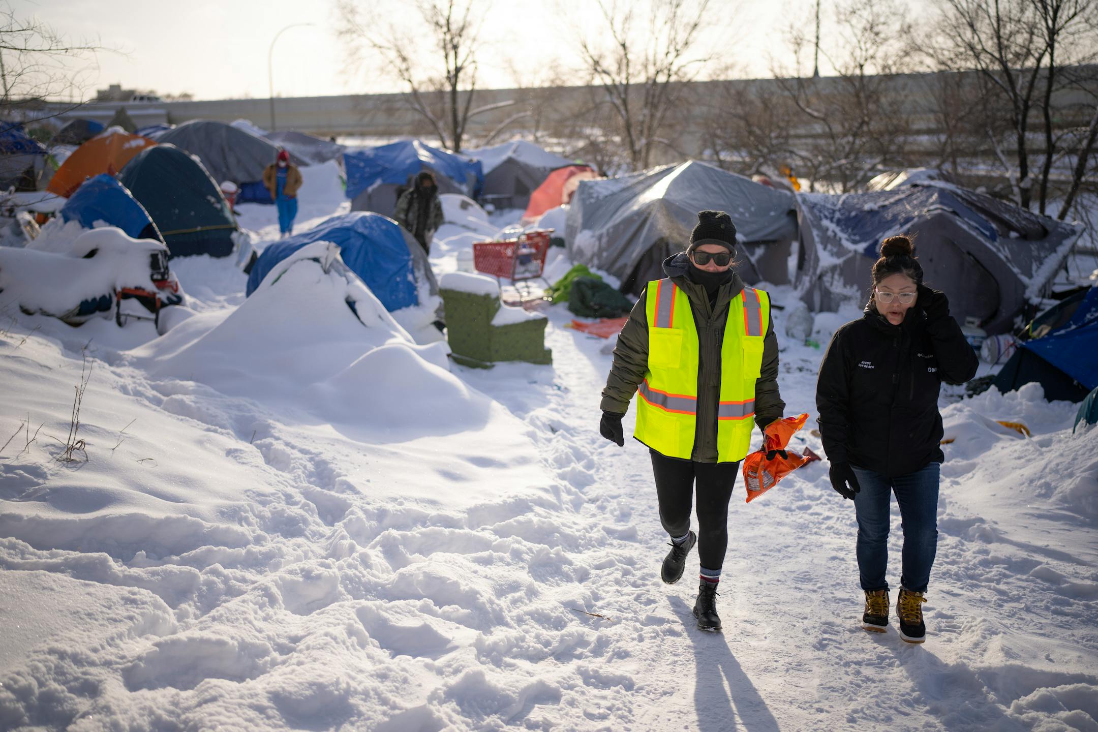 Outreach workers Leah Skjefte, left, and Dava Beaulieu, headed back to their van after distributing hand warmers and snacks to some residents of an encampment near the Cedar Riverside towers Thursday afternoon. Homeless outreach workers for the American Indian Community Development Corp. (AICDC), checked several homeless encampments to offer hand warmers and snacks or a ride to a shelter on a dangerously cold afternoon in Minneapolis Thursday, December 22, 2022.