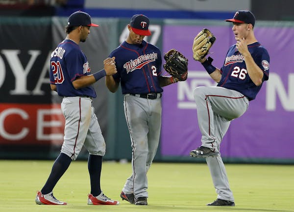 Minnesota Twins' Eddie Rosario (20), Byron Buxton (25) and Max Kepler (26) celebrate in the outfield after their 10-1 win over the Texas Rangers in a 