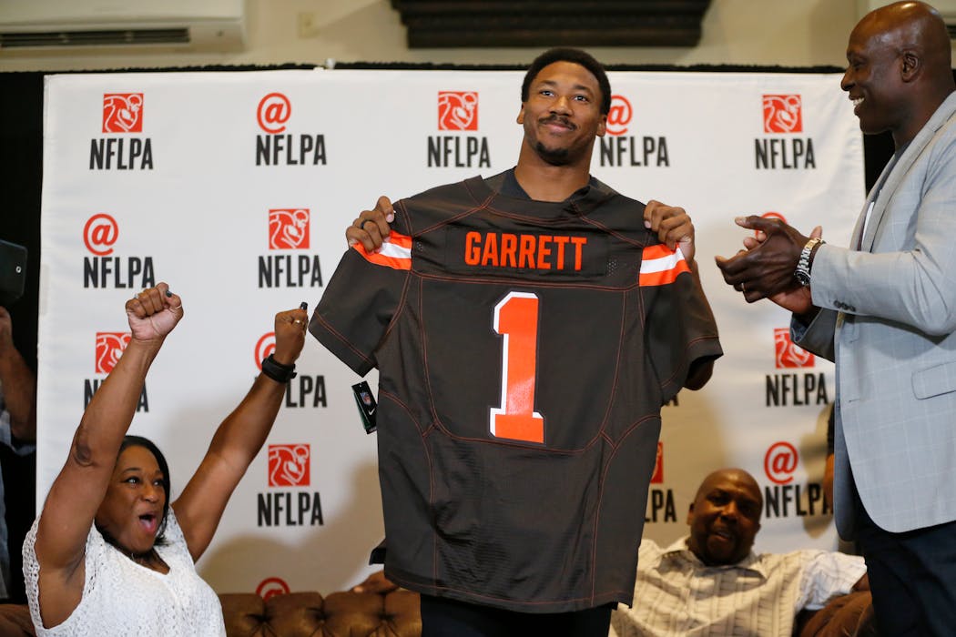 Texas A&M's Myles Garrett holds up a Cleveland Browns jersey as his mother, Audrey Garrett, left, cheers with Bruce Smith