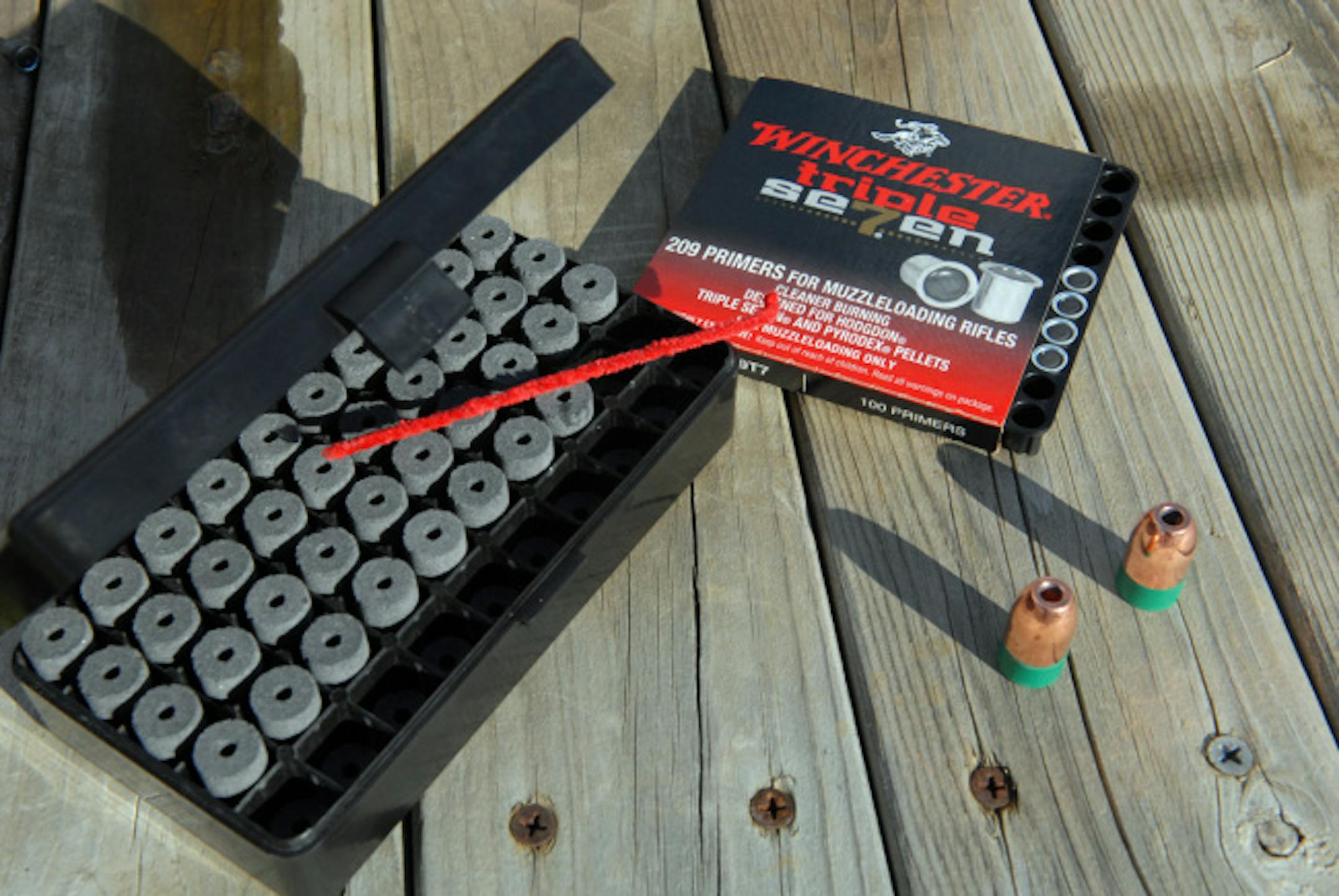 Pressed Triple-Seven pellets, left, 209 primers, center back, and sabot-style bullets, right, provide the firepower for modern in-line muzzleloaders.