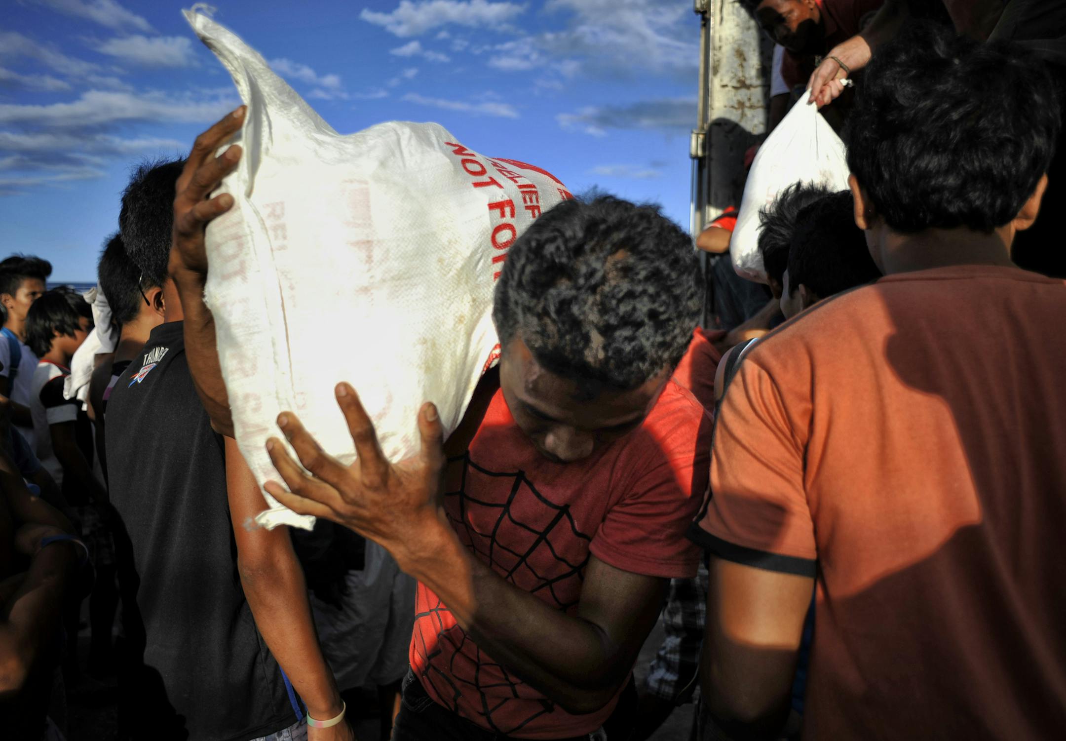 Typhoon victims receive relief goods in Tacloban, the Philippines, Nov. 19, 2013. More than a week after Typhoon Haiyan, the Philippines faces a multitude of questions about the needs of some 13 million people affected by the storm. (Jes Aznar/The New York Times)