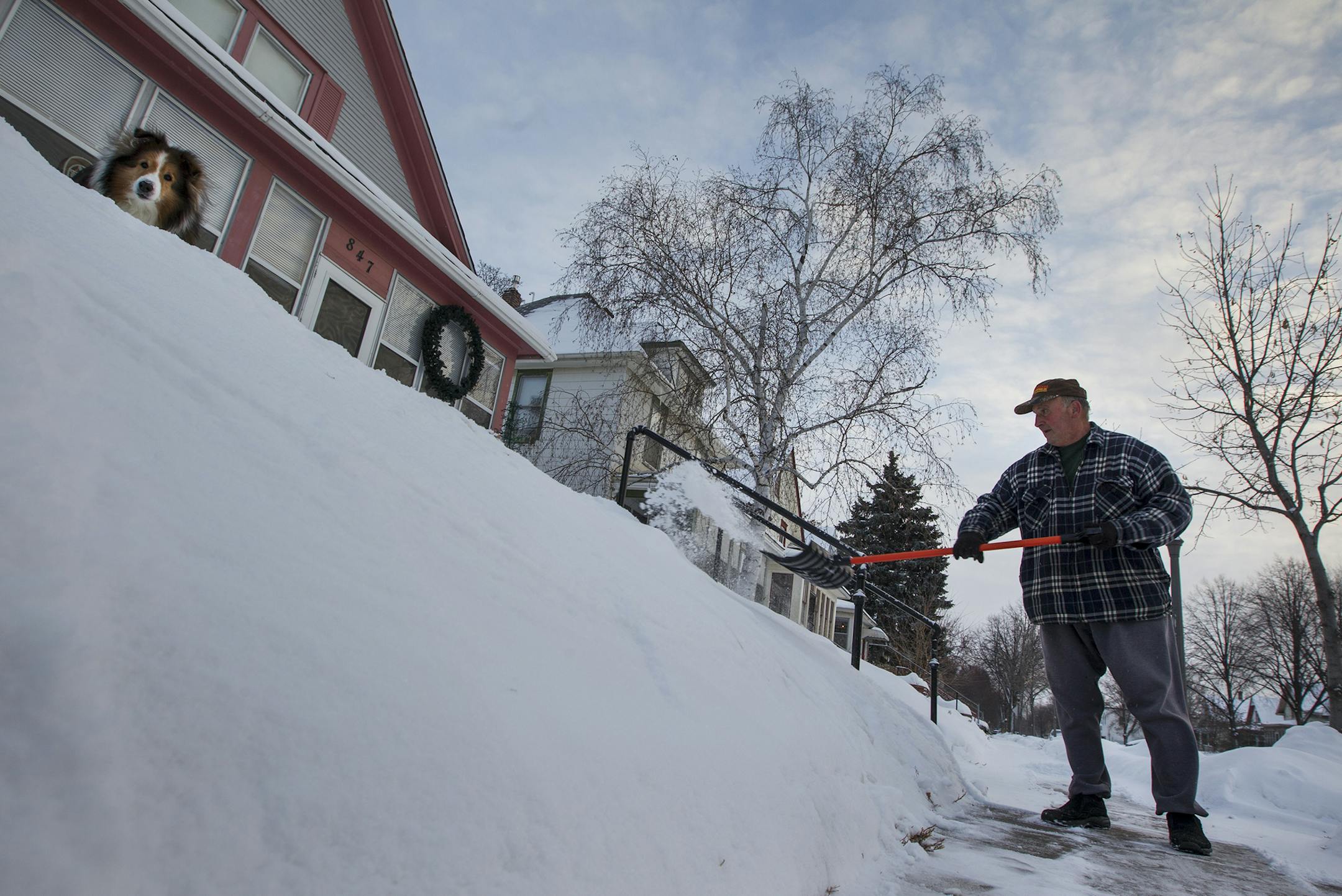 Carl Roith, who has lived in his house on Thomas Avenue in St. Paul for 65 years, shoveled a neighbor’s sidewalk as his dog Weaver kept a close eye on things Monday. Roith said he’d be out shoveling snow no matter how cold it got. Temperatures on Tuesday were expected to climb into the low teens after bitter cold overnight.