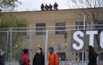 Law enforcement and National Guard stood on the roof of the Brooklyn Center Police Department as protesters gathered outside the fence in response to 