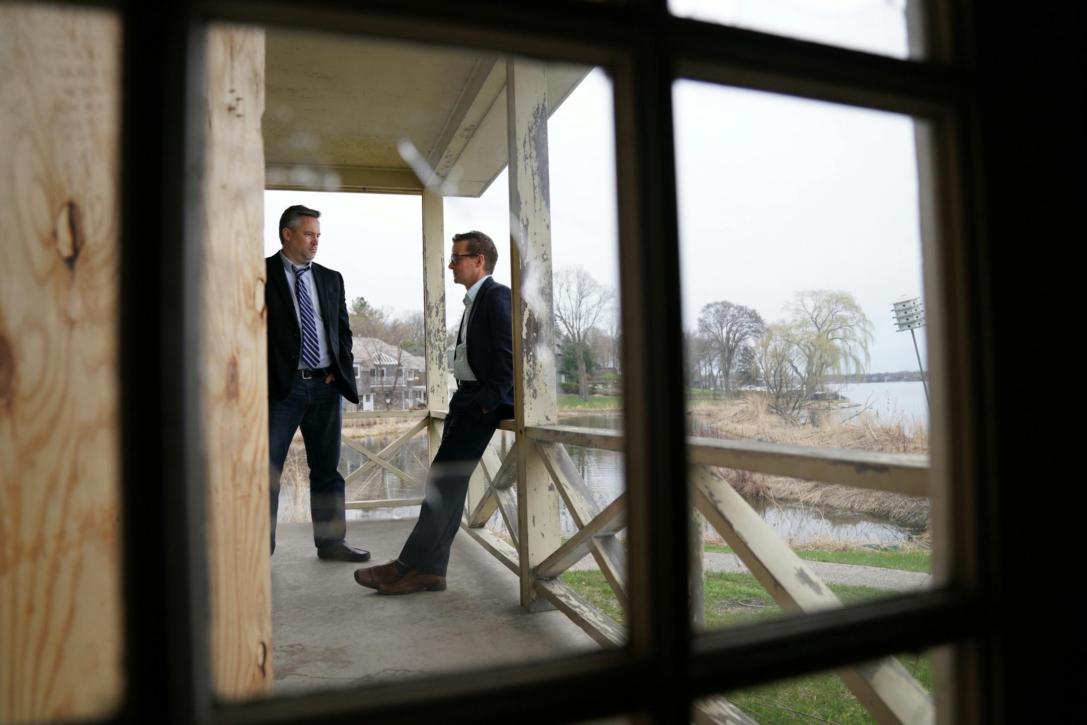 Dan Gustafson with the Heritage Preservation Board, left, and Jeffrey Dahl, Wayzata's city manager, were visible through a broken window pane as they talked on the porch outside the 1902 Section Foreman House Thursday.