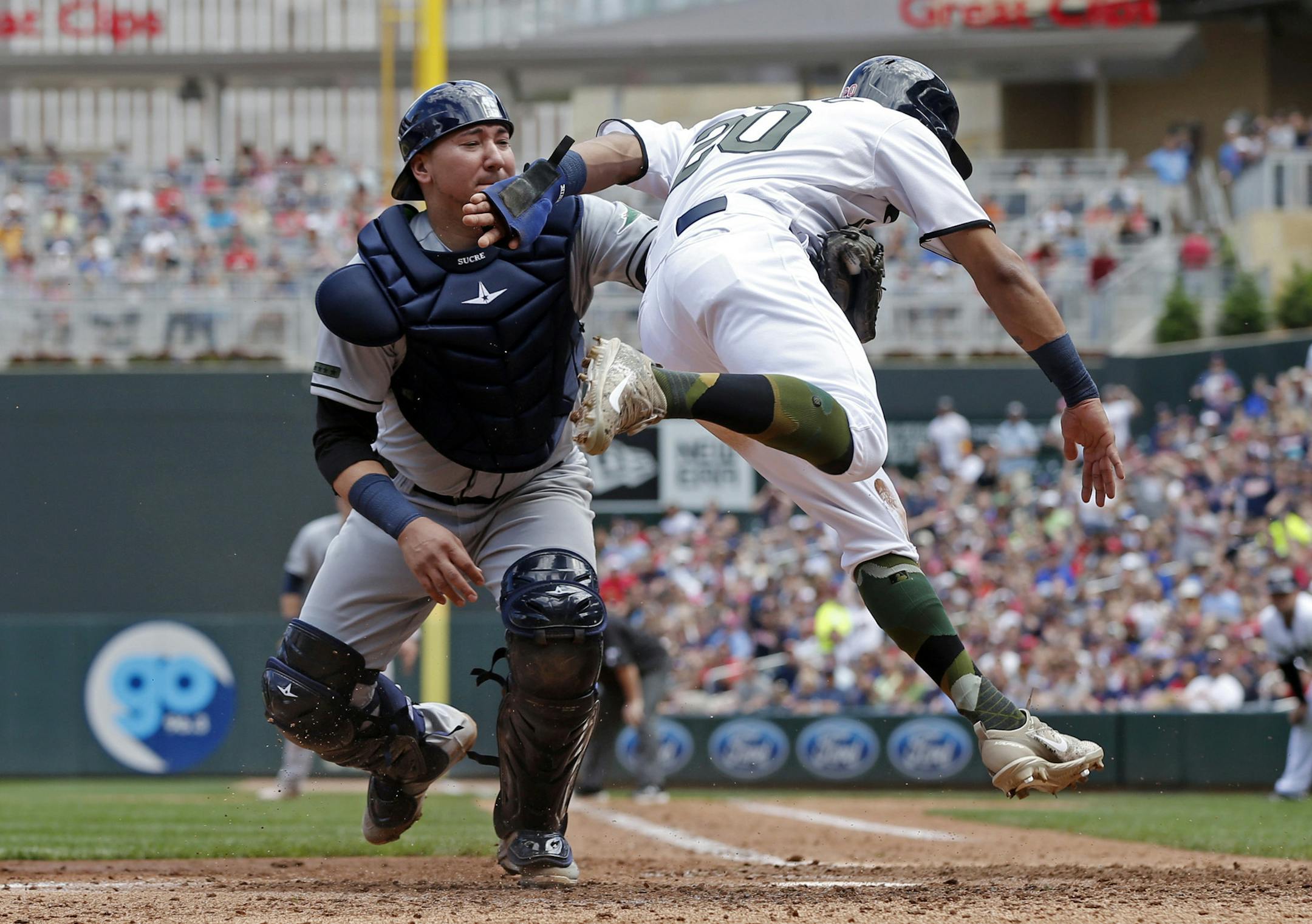 Minnesota Twins' Eddie Rosario,right, tries unsuccessfully to avoid the tag by Tampa Bay Rays catcher Jesus Sucre as he takes to the air trying to score from third in the fourth inning of a baseball game Sunday, May 28, 2017 in Minneapolis. (AP Photo/Jim Mone)