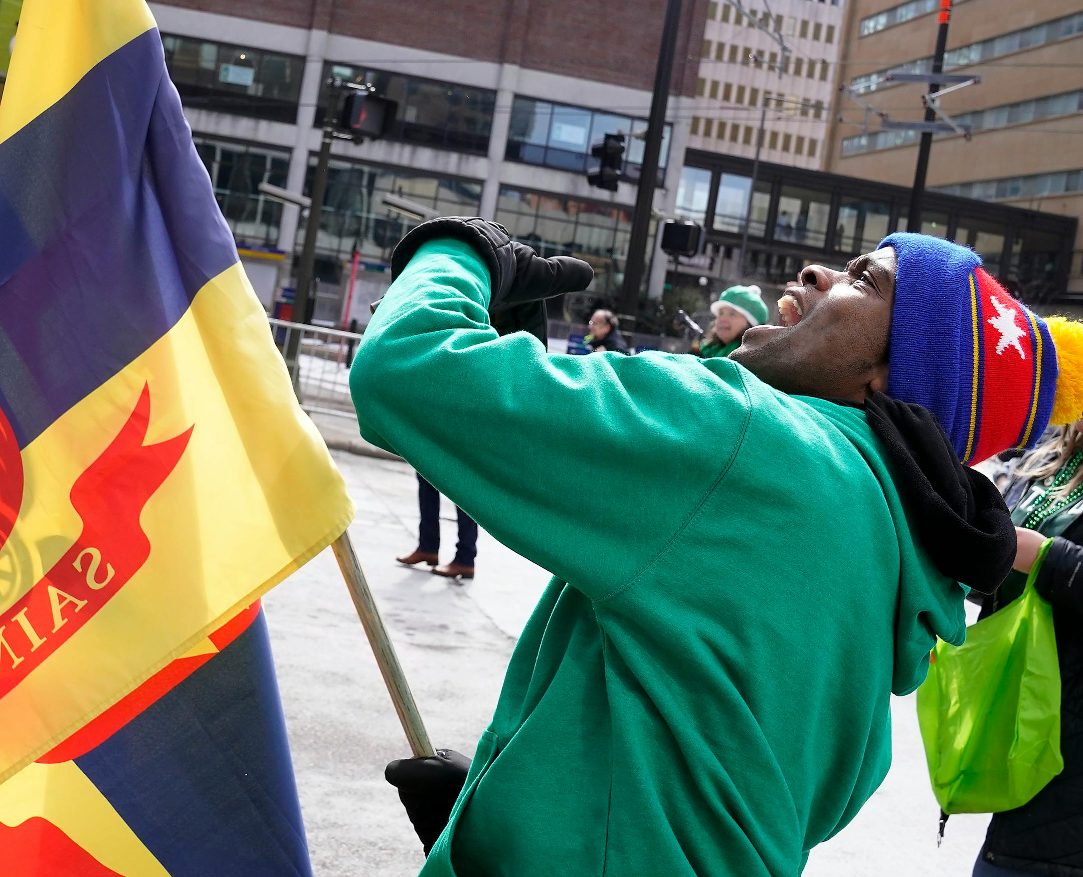 St. Paul Mayor Melvin Carter waves to people in a skyway above him to come on down during the St. Paul's St. Patrick's Day parade below them.