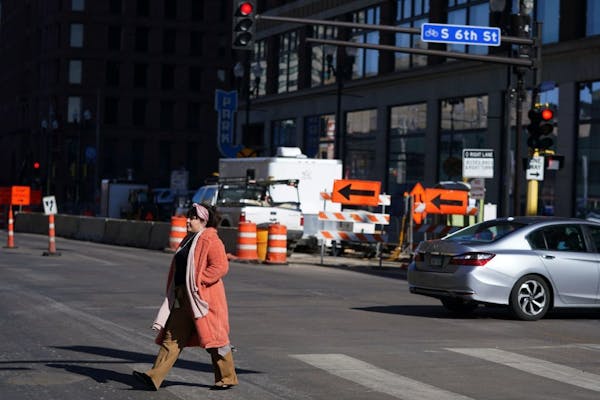 A pedestrian crossed Hennepin Avenue downtown as construction crews worked in the background in February. The downtown Minneapolis thoroughfare is ope