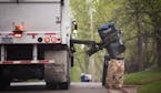 A GarbageMan worker empties containers onto the truck on trash pickup day in Bloomington between France Avenue and Normandale Boulevard on Thursday, M