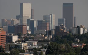 A smoky haze envelopes the skyscrapers and Rocky Mountains that usually can be seen as a backdrop to the city from a high-rise building Monday, Aug. 2