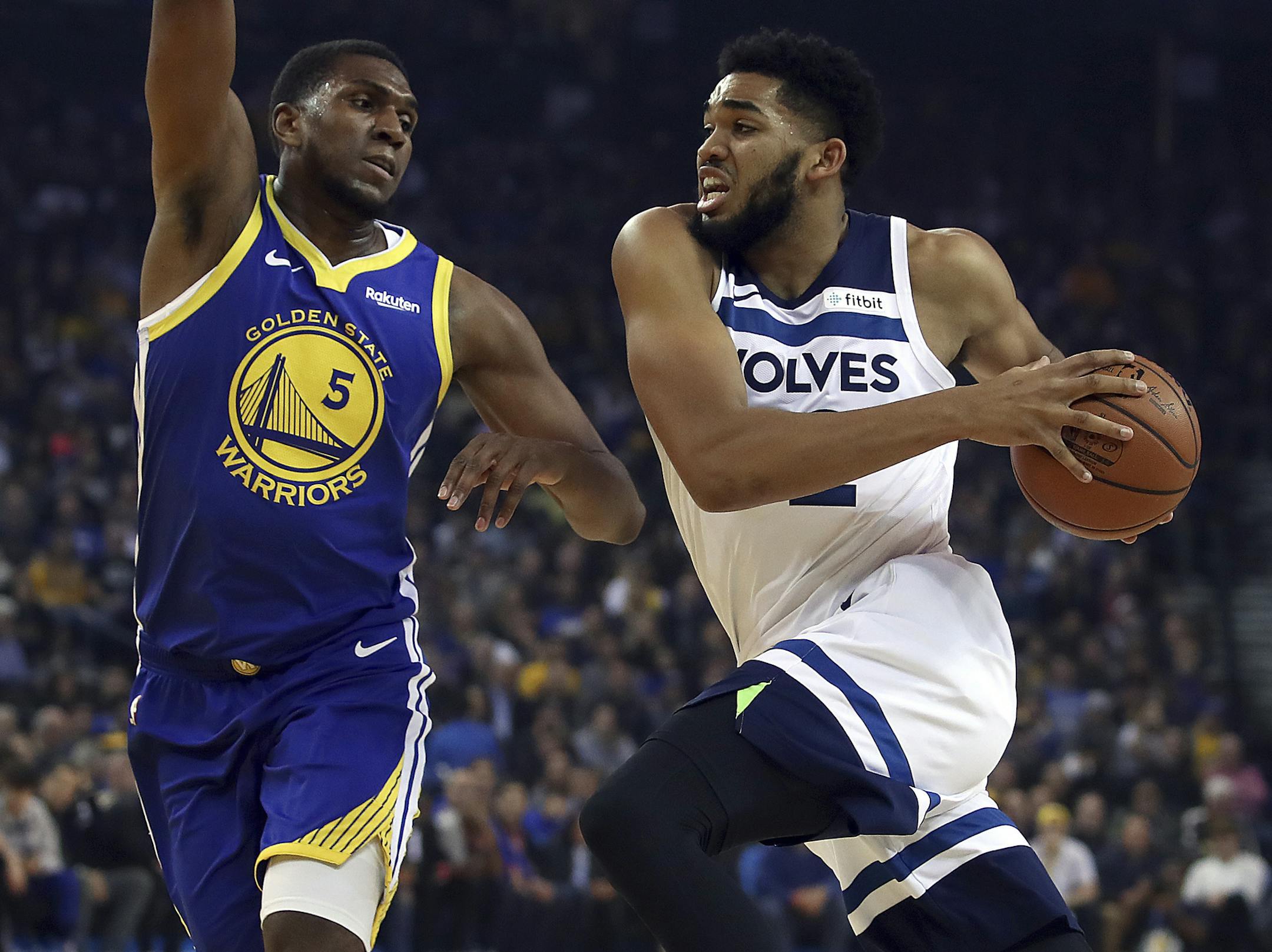 Minnesota Timberwolves' Karl-Anthony Towns, right, drives the ball against Golden State Warriors' Kevon Looney during the first half of an NBA basketball game Monday, Dec. 10, 2018, in Oakland, Calif. (AP Photo/Ben Margot)