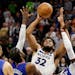 Minnesota Timberwolves center Karl-Anthony Towns (32) shoots on Los Angeles Clippers guard Paul George, left, and Clippers guard Reggie Jackson, right