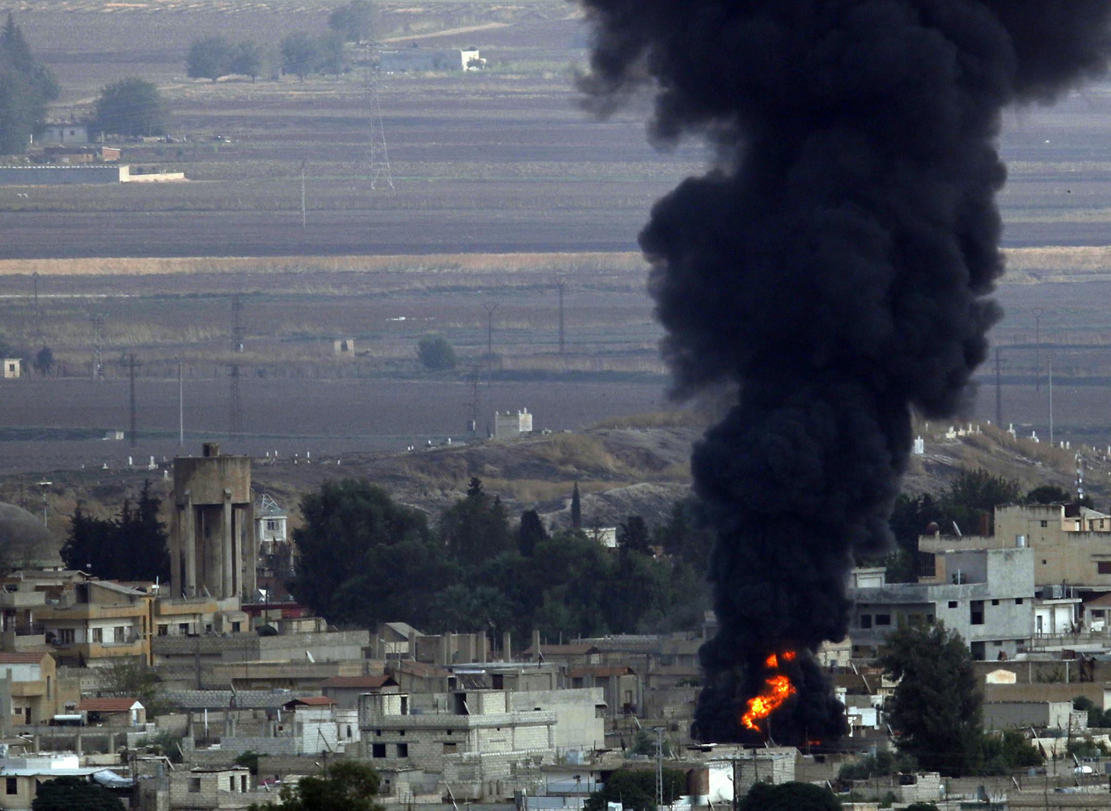 In this photo taken from the Turkish side of the border between Turkey and Syria, in Ceylanpinar, Sanliurfa province, southeastern Turkey, flames and smoke billow from a big fire in Ras al-Ayn, Syria, caused by bombardment by Turkish forces, Wednesday, Oct. 16, 2019. Turkey's President Recep Tayyip Erdogan called Wednesday on Syrian Kurdish fighters to leave a designated border area in northeast Syria 'as of tonight' for Turkey to stop its military offensive. (AP Photo/Lefteris Pitarakis)