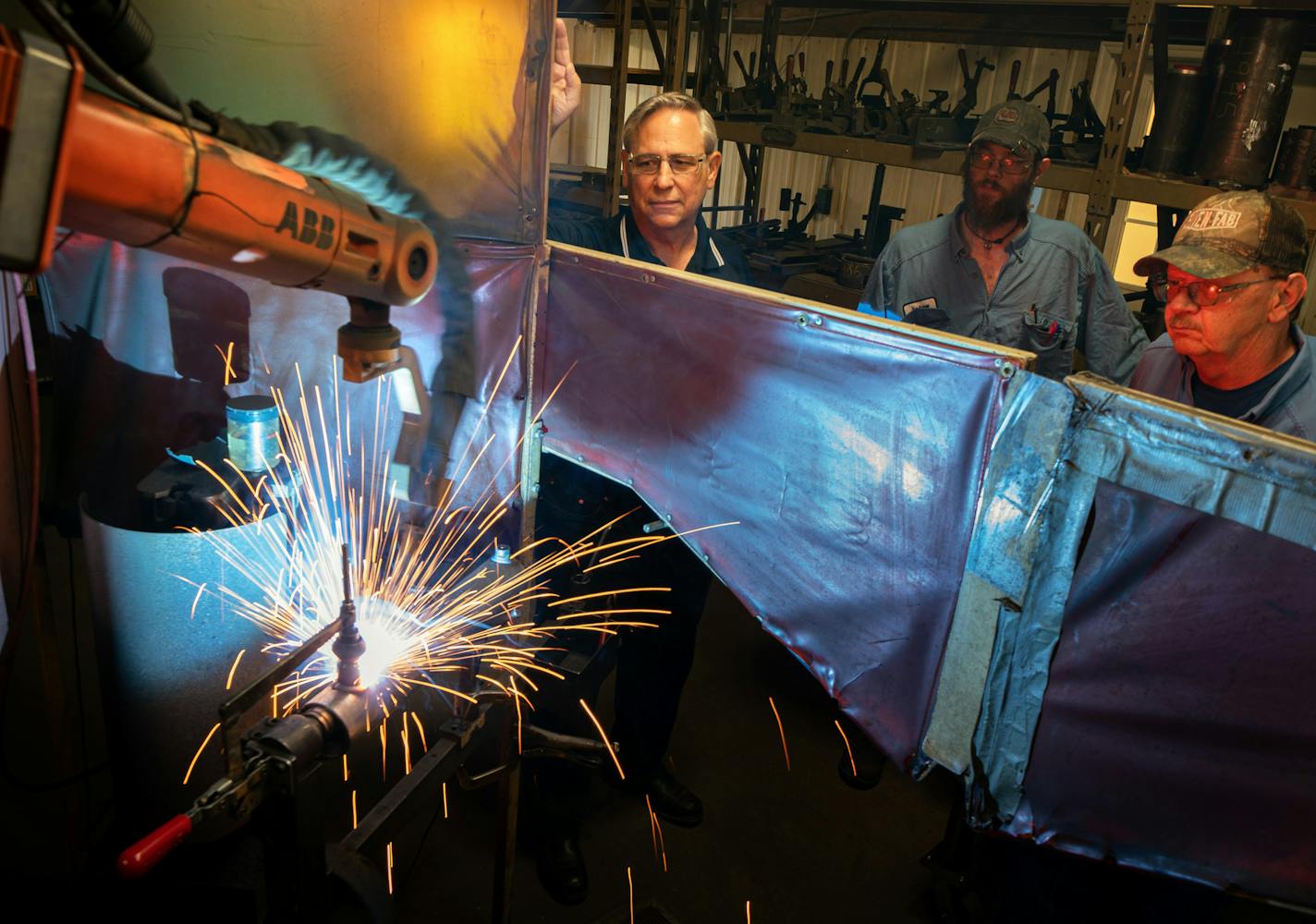 Loren Nelson, left, bought robotic welders for his Braham, Minn., equipment shop. Andrew Kinard, center, is training Wayne Nieson.