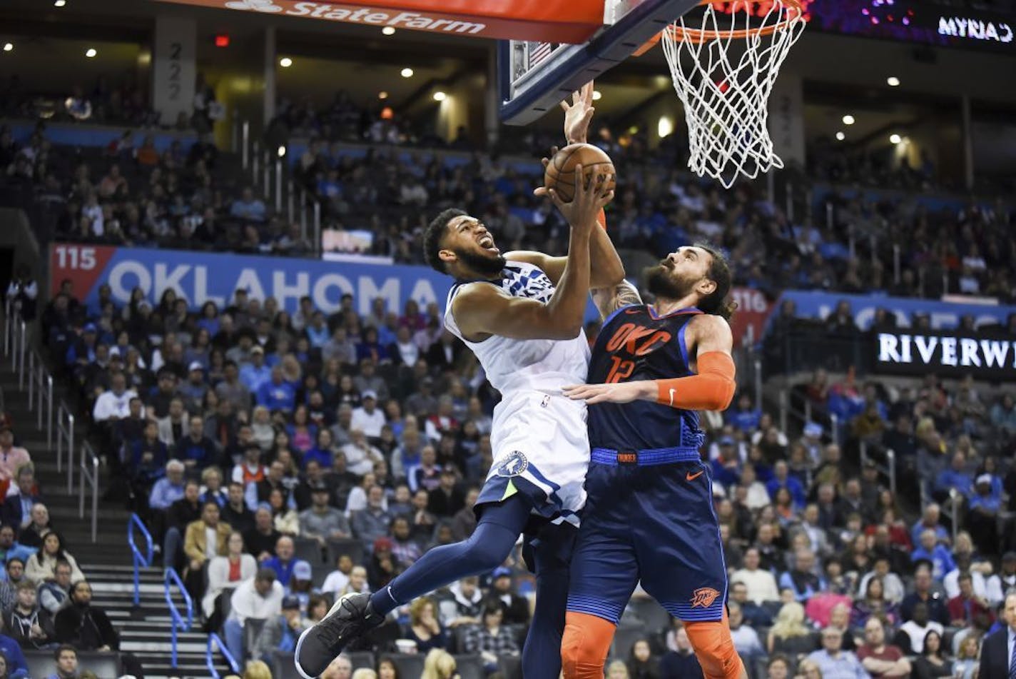 Minnesota Timberwolves center Karl-Anthony Towns, left, goes up to shoot over Oklahoma City Thunder center Steven Adams, right, in the first half of an NBA basketball game in Oklahoma City, Sunday, Dec. 23, 2018.