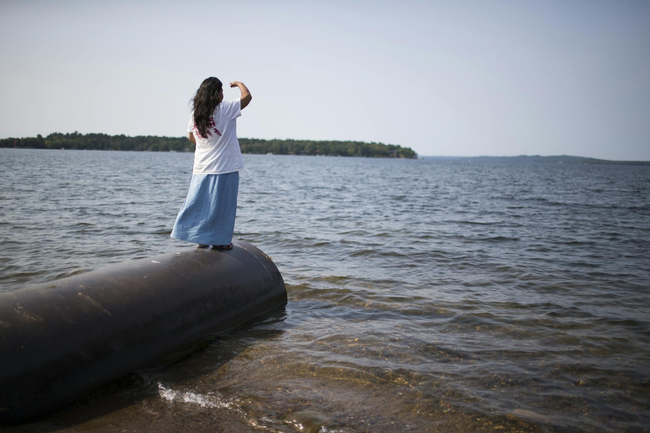 Tania Aubid stands on the culvert into Gull Lake, watching as two members of the tribe set a gill net on Gull Lake.