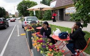 Shanay Ponder, left, answers a call while she sits with her mother, Inez Howard, at the new parklet seating outside of Twin Cities Coffee and Deli on