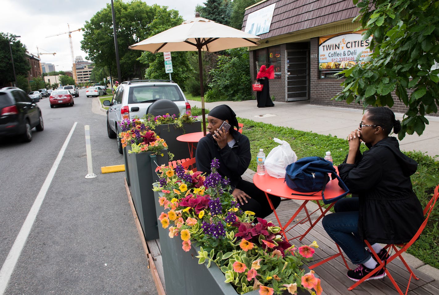 Shanay Ponder, left, answers a call while she sits with her mother, Inez Howard, at the new parklet seating outside of Twin Cities Coffee and Deli on Chicago Ave. on Wednesday. "This is the first time I've seen it," said Ponder of the new seating. "I love it." ] Isaac Hale � isaac.hale@startribune.com The city is expanding its Parklet program to include "street cafes", pop-up spaces to eat in curbside parking spots outside restaurants.