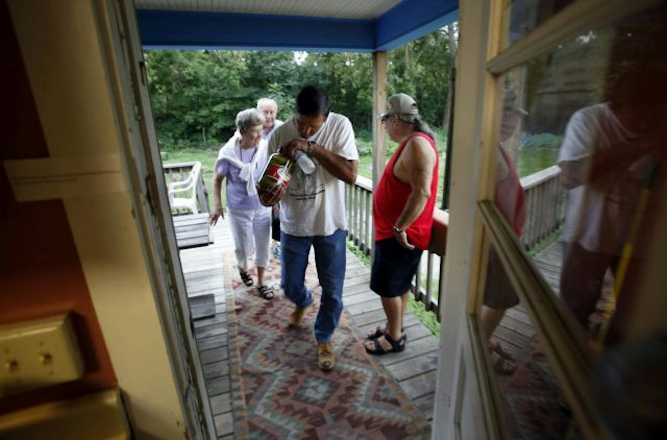 Curt LaClaire, tribal chairman, front, looks over a jar of pickles brought to the center by members June and Dick LeClaire, rear for the tribe's upcoming pow wow. At right is Bear (only name), a Northern Cheyenne from Lame Deer, MT, who now lives in the Twin Cities area, and spends time at the center.