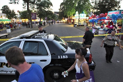 Police adjust crime scene tape at the intersection of Dan Patch Ave and Cooper St. at the State Fair where a knife stabbing incident occurred Sunday evening.