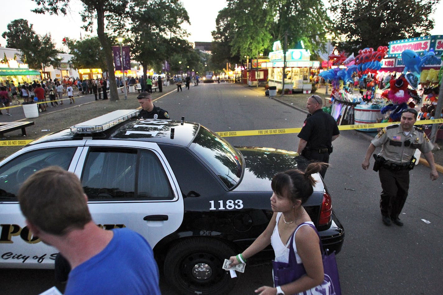 Police adjust crime scene tape at the intersection of Dan Patch Ave and Cooper St. at the State Fair where a knife stabbing incident occurred Sunday evening.