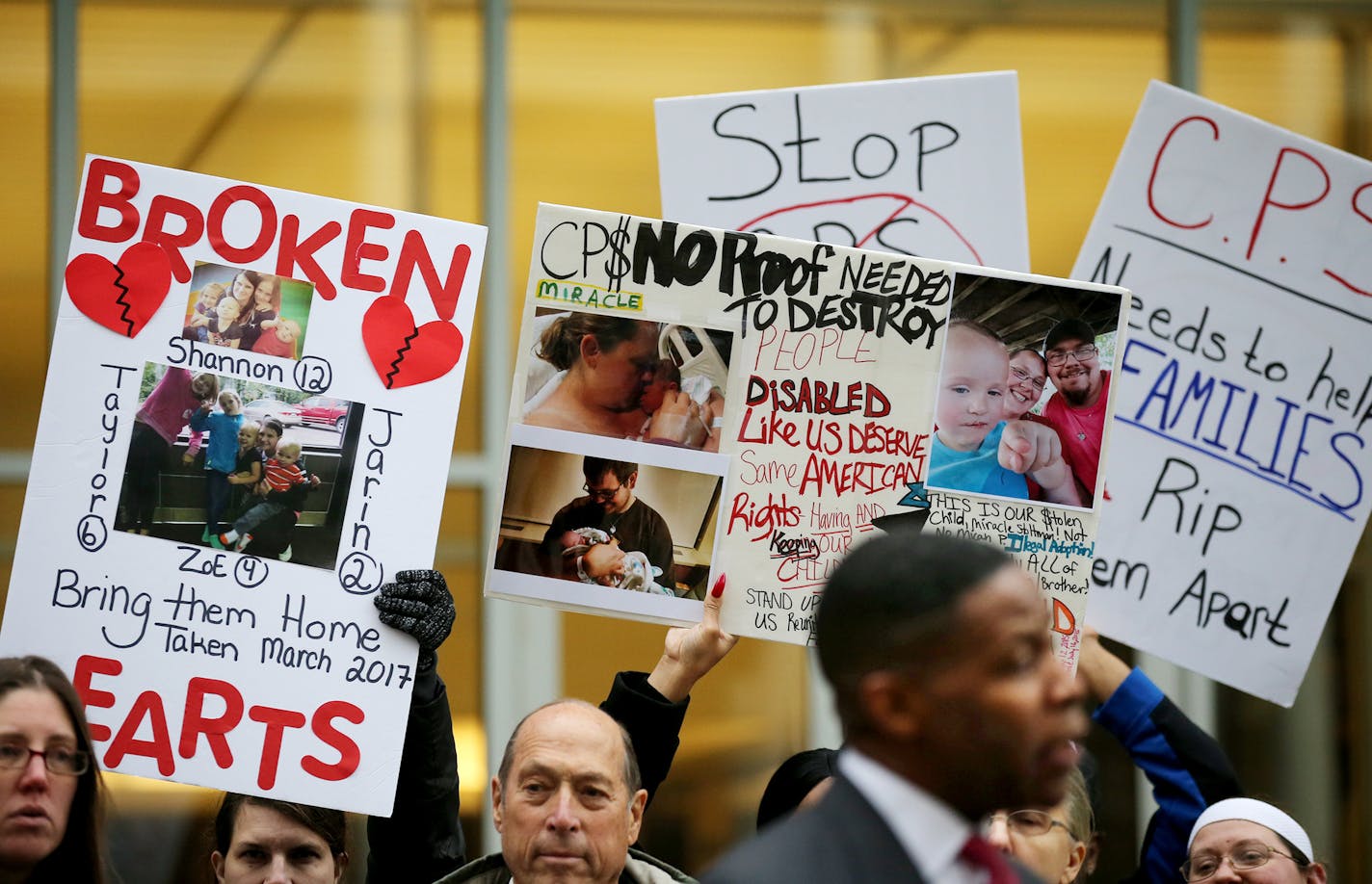 Supporters held signs as Dwight Mitchell talked with with a reporter outside the Federal Building before his lawsuit accusing county and state social service agencies of wrongfully removing children from safe and loving homes and heard Tuesday, Oct. 9, 2018, in St. Paul, MN. His attorneys made opening arguments in Federal Court Tuesday morning in a federal civil rights case in which Mitchell, the plaintiff, alleges that his two children were wrongly removed from his home and placed in foster car