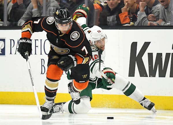Anaheim Ducks left wing Andrew Cogliano, left, takes the puck next to Minnesota Wild left wing Jason Zucker during the second period of an NHL hockey 