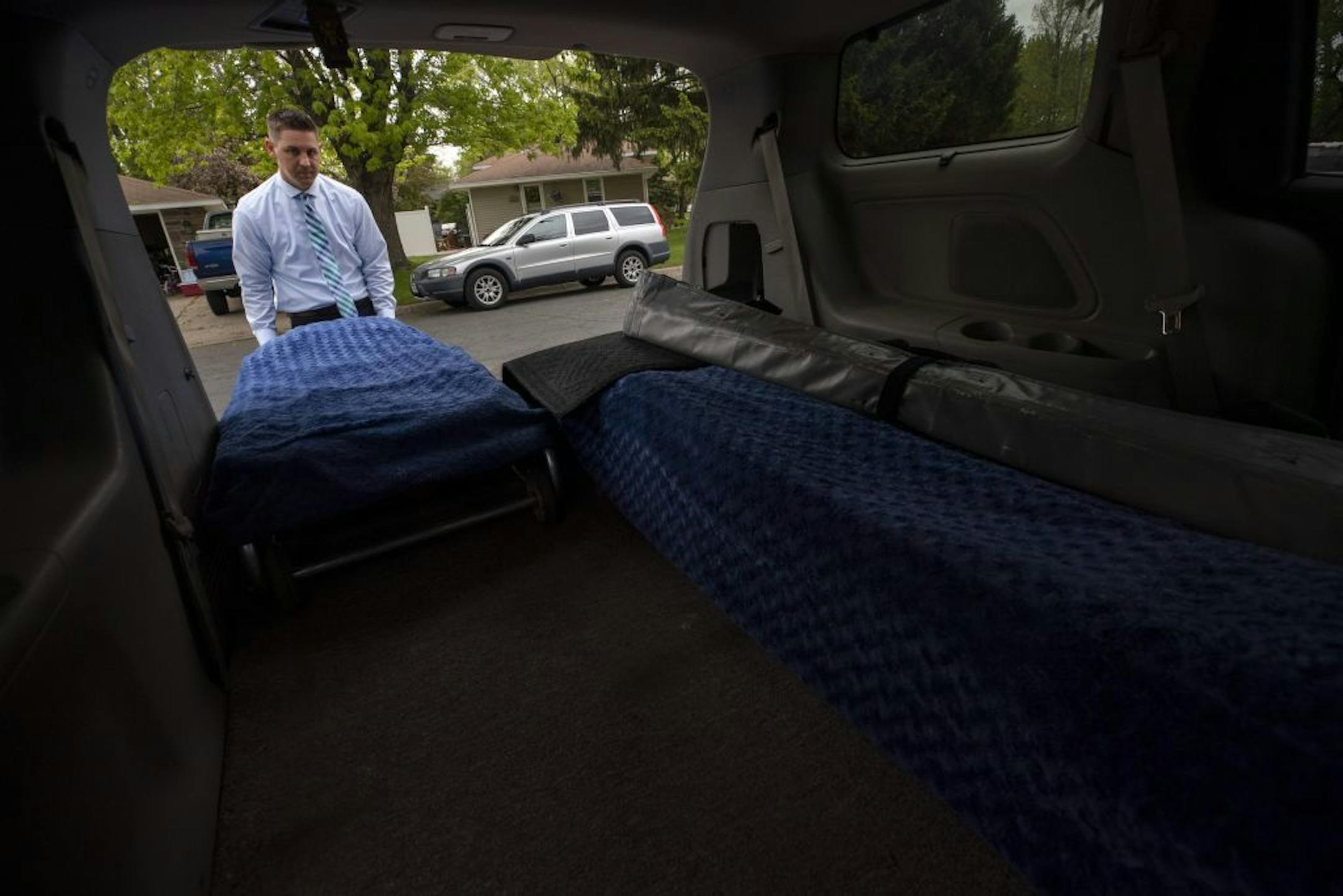 Funeral director Aaron Stromberg demonstrated pulling out a stretcher from his van.