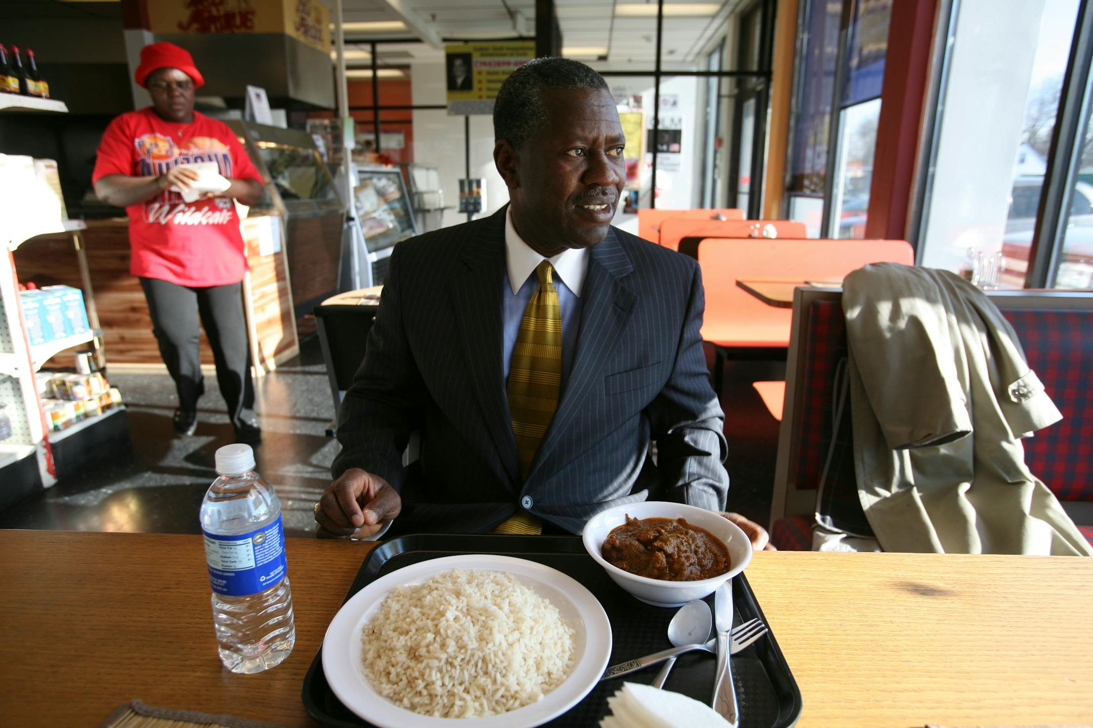 James Sanigular, one of the owners of the Pan-African Market in Crystal, sits down to a meal of palm butter, which is chicken cooked in a savory stew.