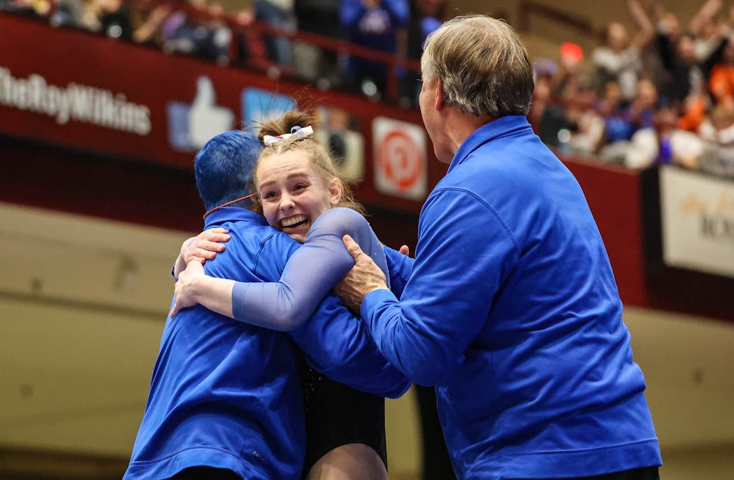 Reagan Kelley celebrated with her coaches Saturday at the Class 1A gymnastics state meet.