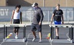 A coach stands by as students run a drill during a strength and conditioning camp at a high school in Arlington, Texas, last month.