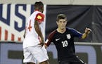 United States' Christian Pulisic (10) tries to moves the ball around Trinidad & Tobago's Andre Boucaud (14) during the first half of a CONCACAF World 