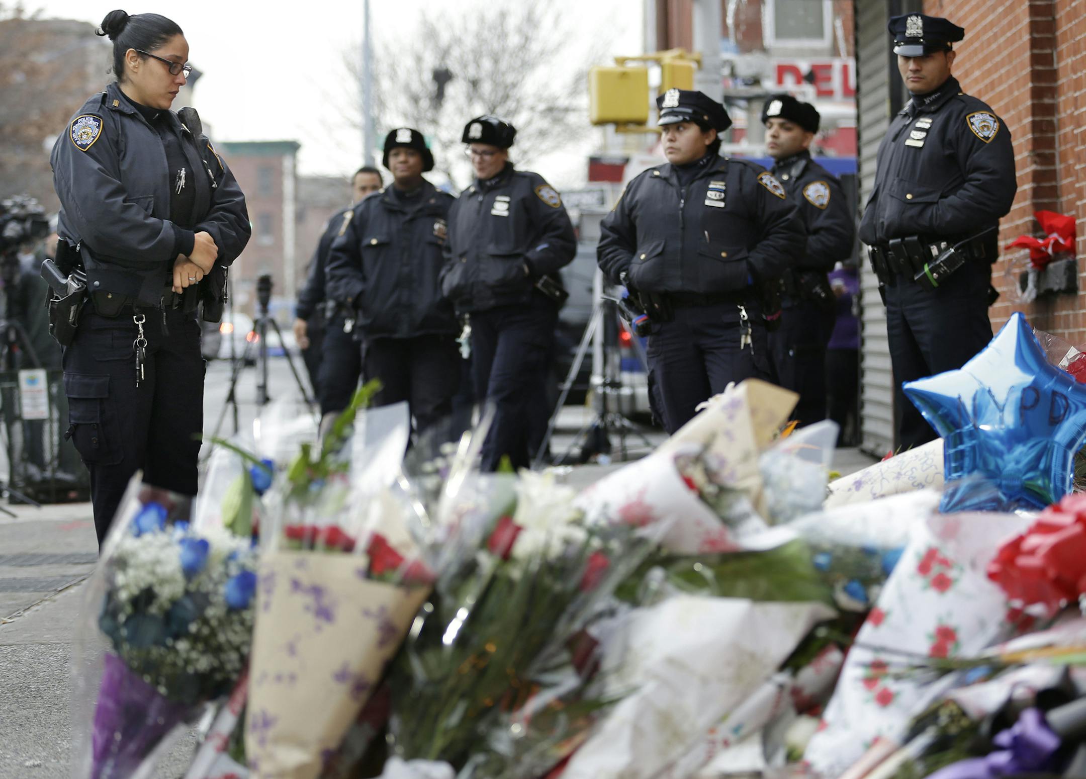 Police officers pay their respects at a makeshift memorial near the site where New York City police officers Rafael Ramos and Wenjian Liu were murdered, in the Brooklyn borough of New York, Monday, Dec. 22, 2014. Police say Ismaaiyl Brinsley ambushed the two officers in their patrol car in broad daylight Saturday, fatally shooting them before killing himself inside a subway station. (AP Photo/Seth Wenig) ORG XMIT: MIN2014122214325700