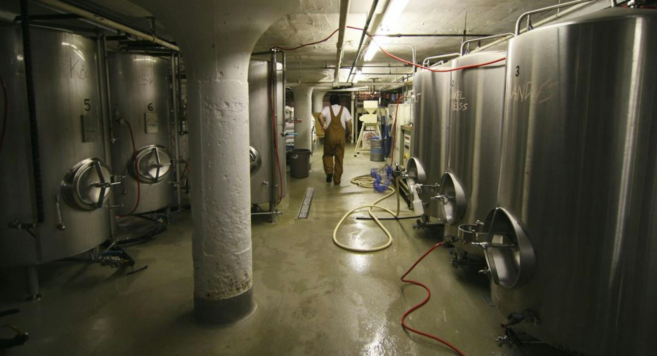 Gustavo Vale walks throught the tanks of fermenting beer in the basement of the Herkimer pub and brewery