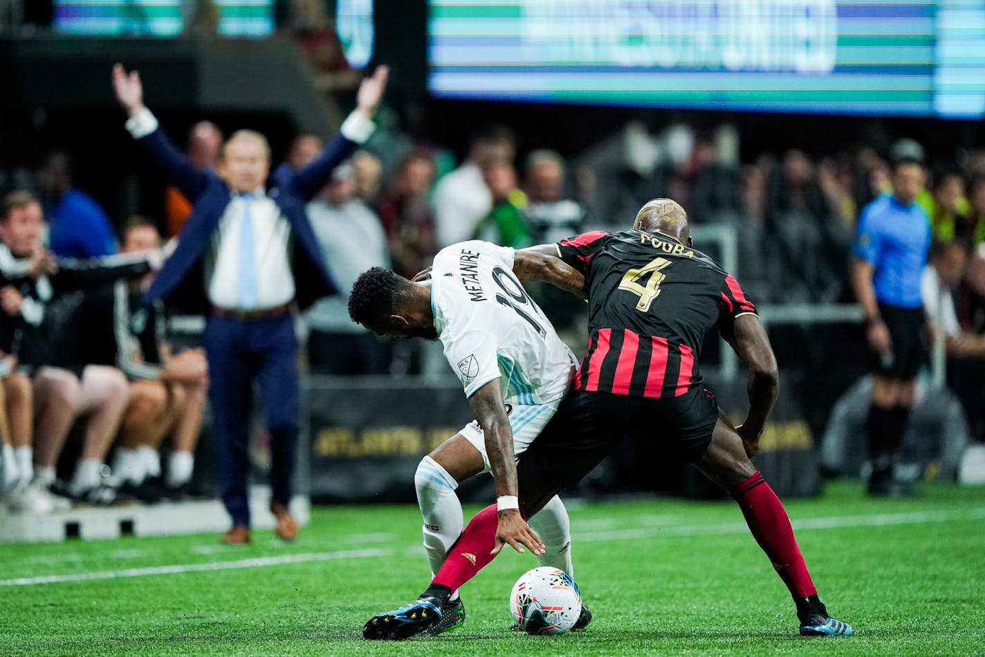 Minnesota United defender Romain Metanire (19) and Atlanta United defender Florentin Pogba (4) battle for the ball as Minnesota head coach Adrian Heath reaches in the background