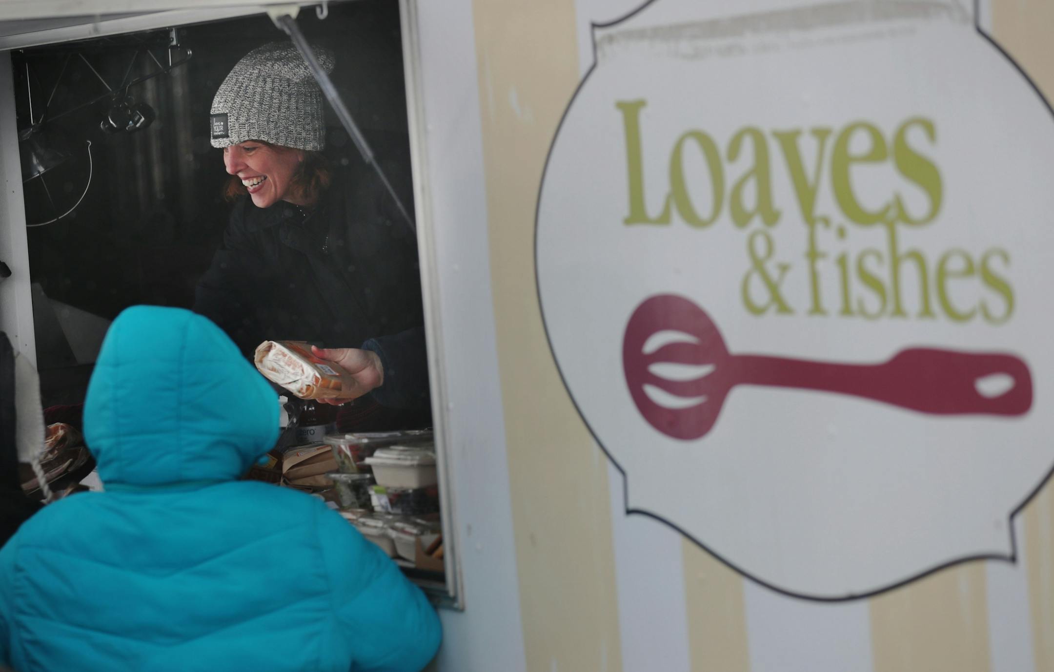 The local non-profit, Loaves and Fishes has partnered with the MSP Airport and concessionaire HMS Host to donate ready-to-eat meals not purchased at the airport, that would otherwise be thrown away, to the homeless near the Dorothy Day Center Thursday, Dec. 28, in St. Paul, MN. Here, Cathy Maes, Loaves and Fishes executive director, hands out sandwiches.