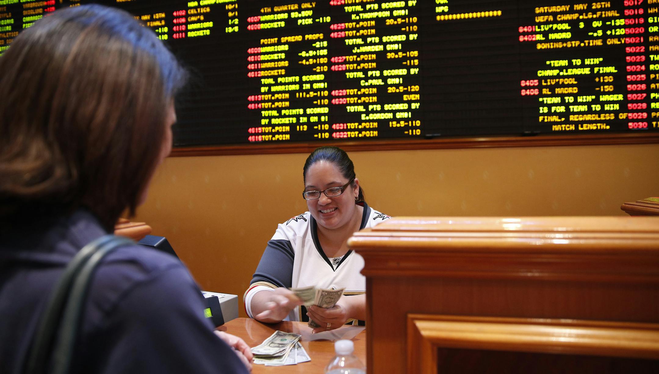 Crystal Kalahiki pays out a bet in the sports book at the South Point hotel-casino, Monday, May 14, 2018, in Las Vegas. The Supreme Court on Monday gave its go-ahead for states to allow gambling on sports across the nation, striking down a federal law that barred betting on football, basketball, baseball and other sports in most states. (AP Photo/John Locher)
