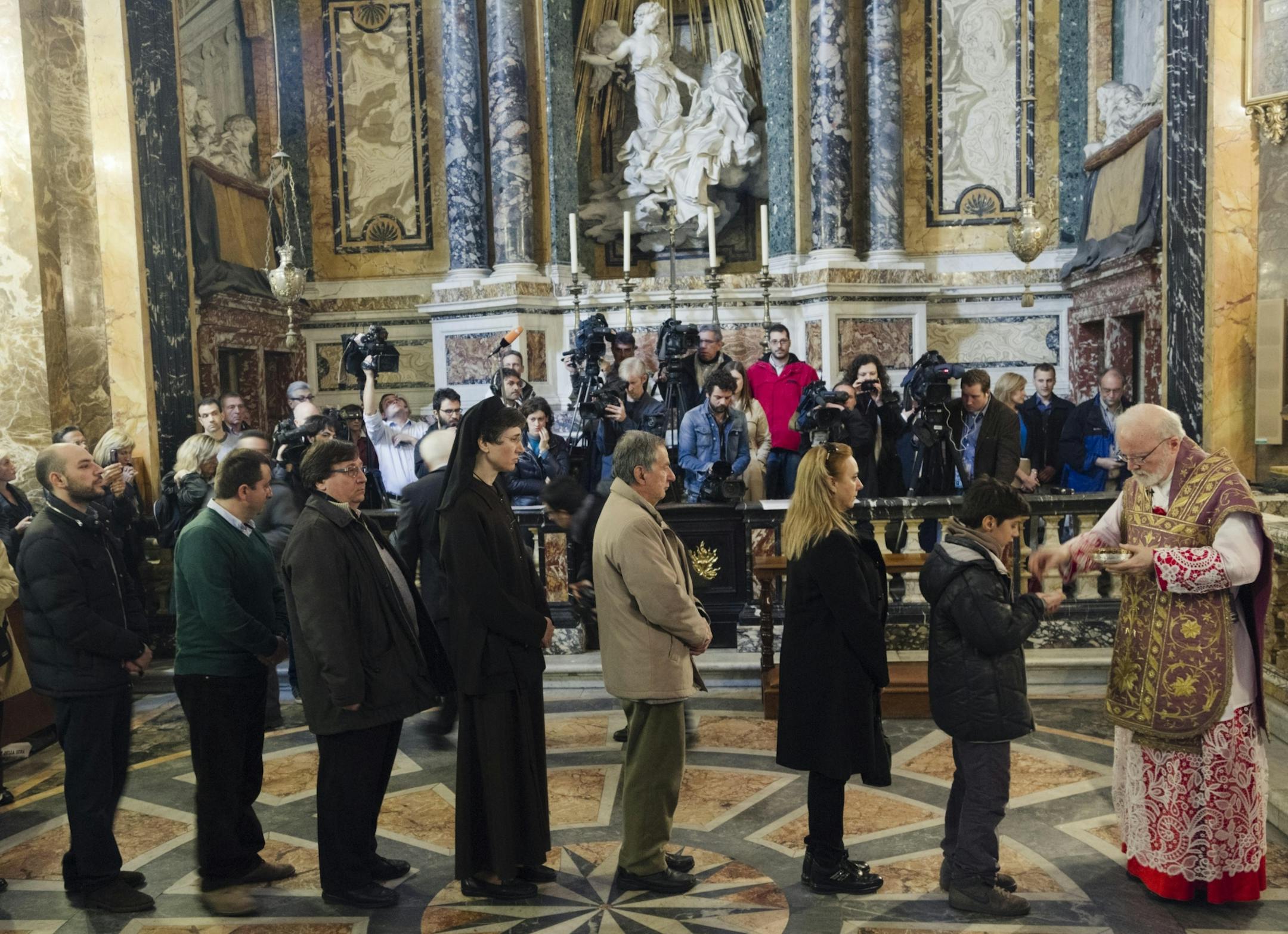 U.S. Cardinal Sean Patrick O'Malley, right, gives the holy communion as he celebrates Mass in his titular church of Santa Maria alla Vittoria in Rome, Sunday, March 10, 2013. Cardinals from around the world gather this week in a conclave to elect a new pope following the stunning resignation of Benedict XVI. In the secretive world of the Vatican, there is no way to know who is in the running, and history has yielded plenty of surprises. Yet several names have come up time repeatedly as strong co