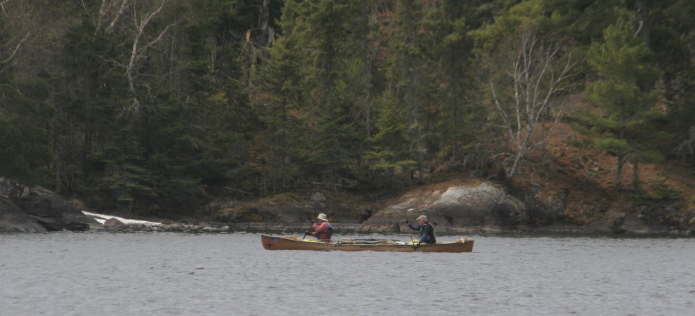 Doug Smith/Star Tribune, May 17, 2013; Besides motorboats and houseboats, canoes also are used in Voyageurs National Park. These two canoers paddled past some snow on the shoreline of Lake Kabetogama on May 17.