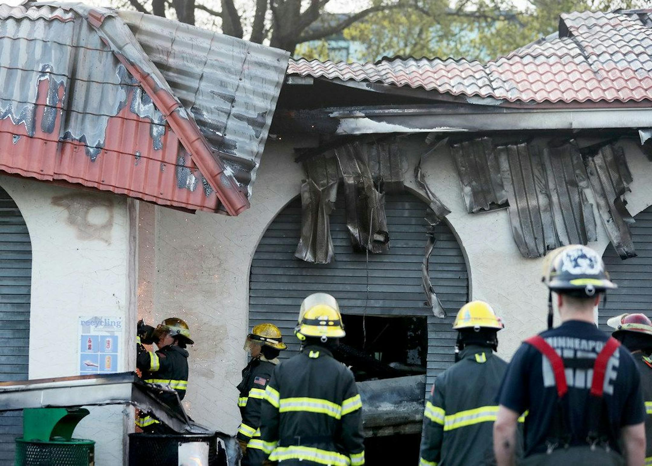 Firefighters mop up the scene after an early morning fire at the Bde Maka Ska pavilion on May 16. A replacement structure will likely not be rebuilt until 2021, according to the Minneapolis Park and Recreation Board.