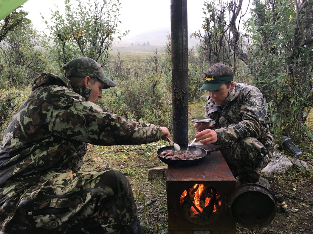 Montanan Ken Juell, left, and Max Kelley cook caribou backstrap on a vintage stove on an Alaskan hunt taken with Trevor Anderson and his dad, Star Tribune columnist Dennis Anderson.