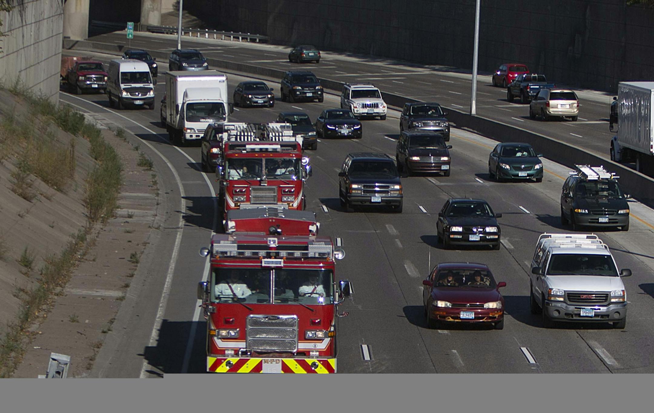 Representatives from 11 fire departments escorted a statue from Howard Lake (where it was treated to endure the outdoor elements) to the Minnesota Fallen Firefighters Memorial at the State Capitol. The procession wound along I-94, here as the trucks passed near Franklin Ave. in Minneapolis.
