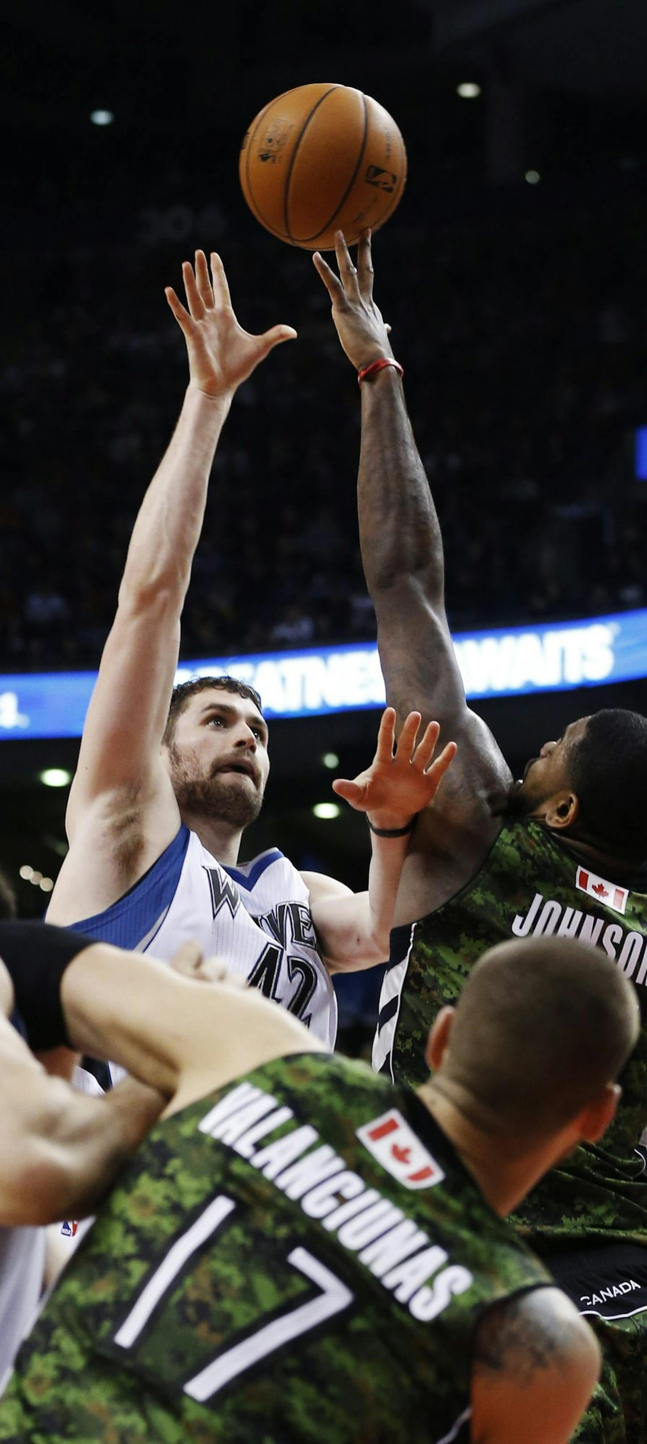 Minnesota Timberwolves' Kevin Love puts up a shot against Toronto Raptors' Amir Johnson, right, during the second half of an NBA basketball game Friday, Jan. 17, 2014, in Toronto. (AP Photo/The Canadian Press, Mark Blinch)