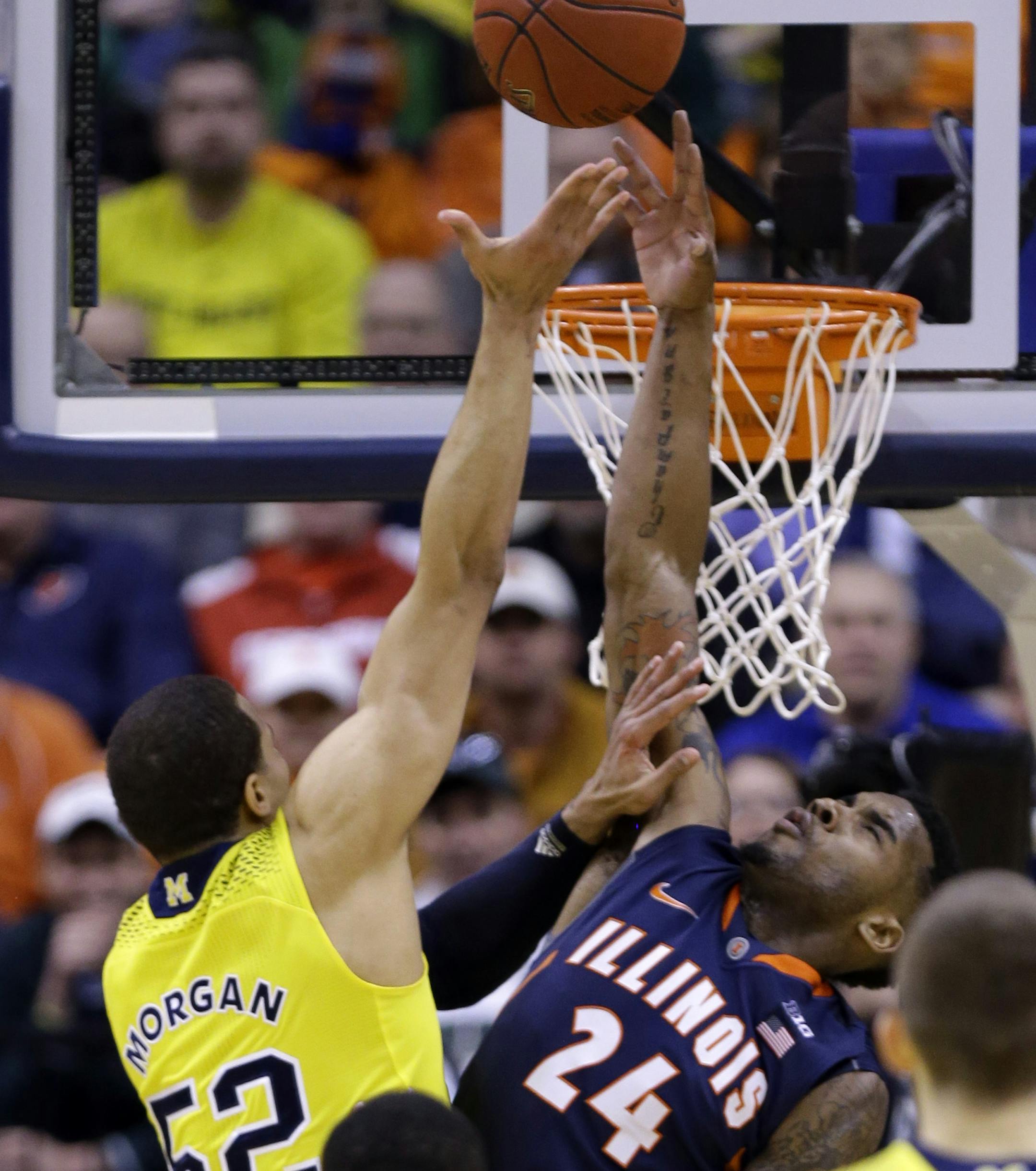 Michigan forward Jordan Morgan, left, hits the game-winning basket over Illinois guard Rayvonte Rice in the closing seconds in the second half of an NCAA college basketball game in the quarterfinals of the Big Ten Conference tournament Friday, March 14, 2014, in Indianapolis. Michigan won 64-63. (AP Photo/Michael Conroy)